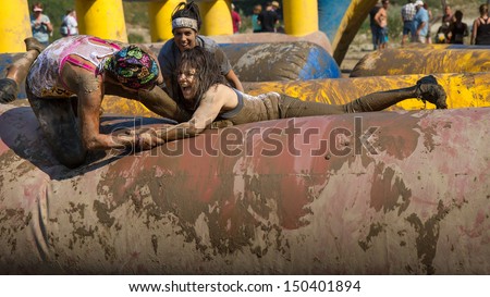 BOISE, IDAHO/USA - AUGUST 10: Two people try to help each other out to finish the course at the The Dirty Dash in Boise, Idaho on August 10, 2013