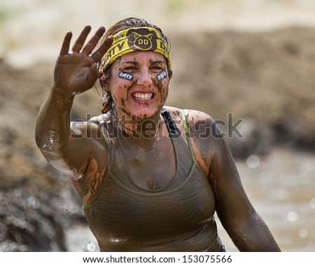 BOISE, IDAHO/USA - AUGUST 11: Woman coverd in mud waves at the camera wearing her dirty dash gear. Event took place at the The Dirty Dash in Boise, Idaho on August 11, 2013