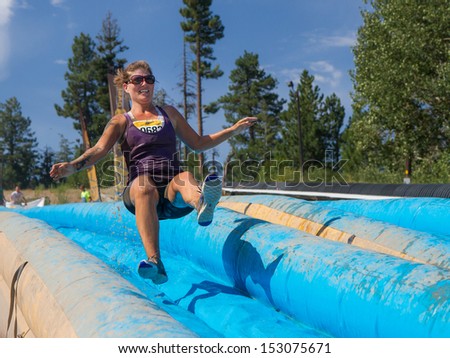 BOISE, IDAHO/USA - AUGUST 11: Runner 9682 jumps on the slide on her way to the finish line at the The Dirty Dash in Boise, Idaho on August 11, 2013