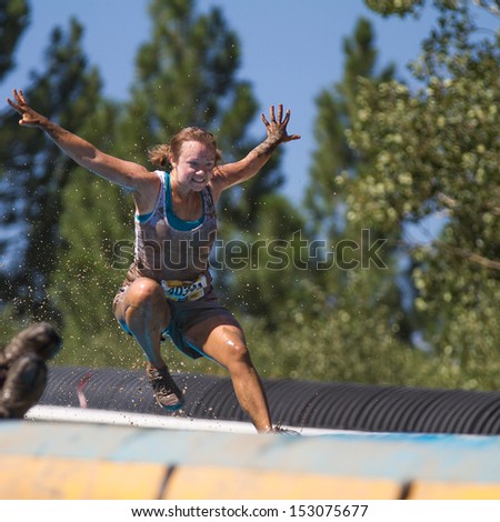 BOISE, IDAHO/USA - AUGUST 10: Runner 40341 jumps on her way down the slide at the The Dirty Dash in Boise, Idaho on August 10, 2013