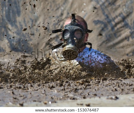 BOISE, IDAHO/USA - AUGUST 10: Unidentified gas masked runner splashes down at the start of the mud pit during the The Dirty Dash in Boise, Idaho on August 10, 2013