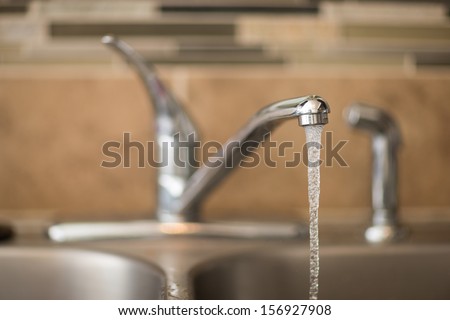 Getting a drink of water from the sink. View has shallow depth of field and is a head on view of a faucet