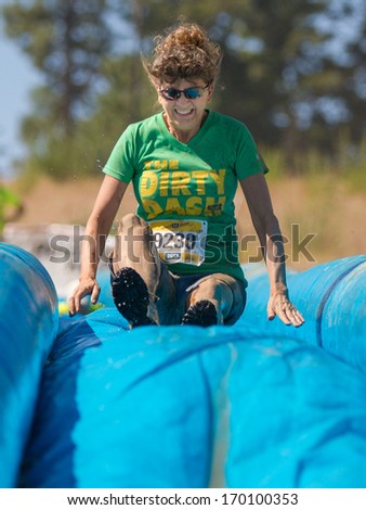BOISE, IDAHO/USA - AUGUST 10, 2013: Runner 9230 goes down the blue slide at the The Dirty Dash