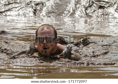 BOISE, IDAHO/USA - AUGUST 11, 2013: Unidentified man swims through the mud pit at the dirty dash