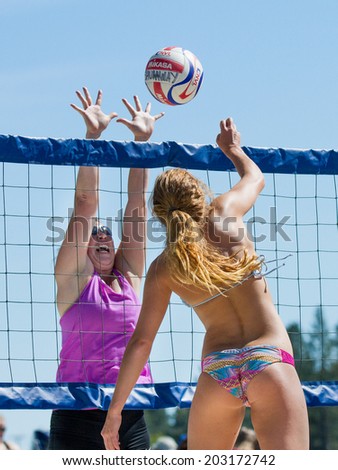CASCADE, IDAHO/USA - JUNE 21, 2014: Unidentified woman trying to spike the ball while another woman attemps a block at the Payette River Games in Cascade, Idaho