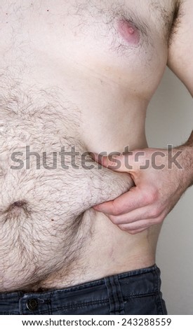 Image of a male grabbing his skin fat. Image is slightly cool