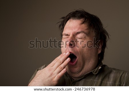 MAn lets out a huge yawn with how tired he is, or is he getting ready to sneeze