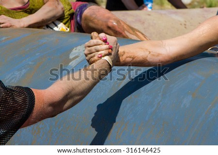 BOISE, IDAHO/USA - AUGUST 11, 2013: Man grabs the hand of a woman to help her at the dirty dash in Boise, Idaho