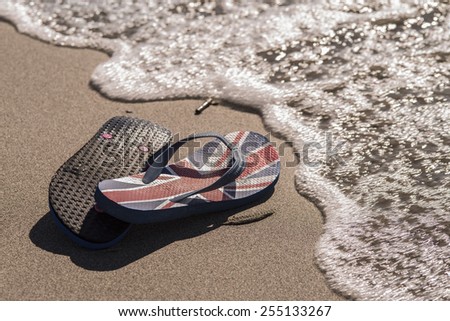 A pair of flip flop sitting on the beach during a sunset / Beach thongs