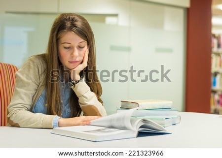 Young woman reading books in the library and studying for exam. Attractive female university student. Education concept