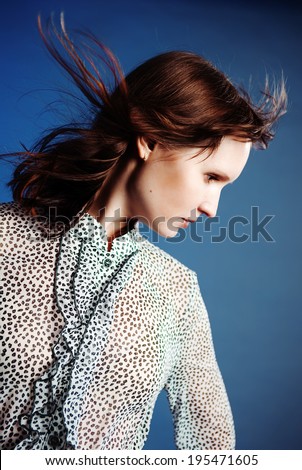 Profile picture of the girl with waving hair on the blue background