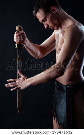 Strong man with ancient sword and  armor on the black background