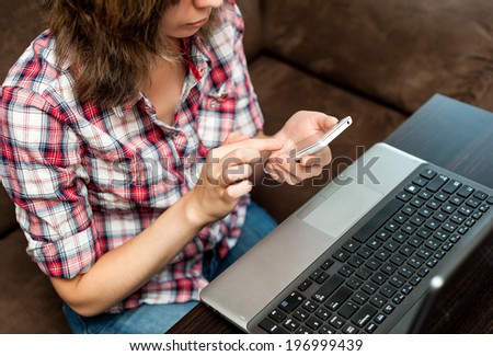 Student with cell phone and laptop siting on the couch