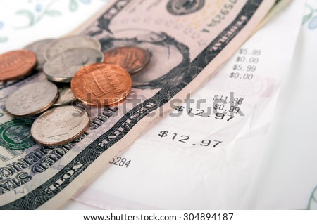 Restaurant bill with dollar bills (tips) on a plate and receipt close up