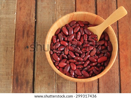 close up of a bowl of red beans and red beans on a wooden spoon