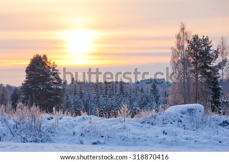 Snow winter landscape and sun shining behind clouds