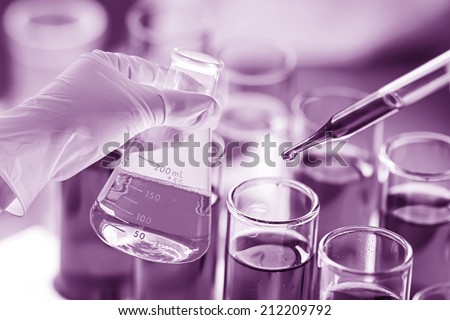 Researcher is dropping the reagent into test tube for reaction testing in chemical laboratory.
