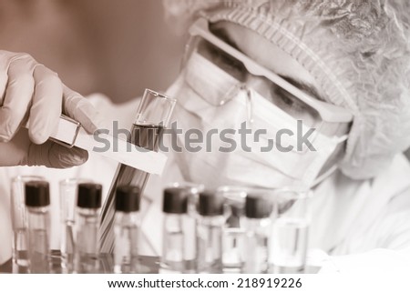 A researcher looking at a test tube of clear solution in a laboratory.