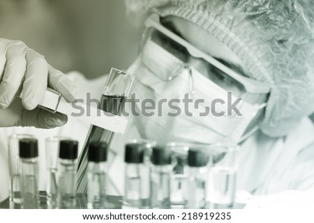 A researcher looking at a test tube of clear solution in a laboratory.