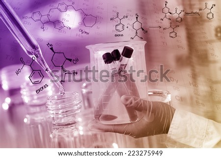 Gloved hand hold a beaker in laboratory room.