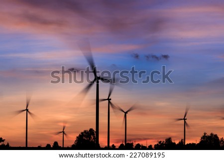 The rotation of the wind turbines silhouette at sunset