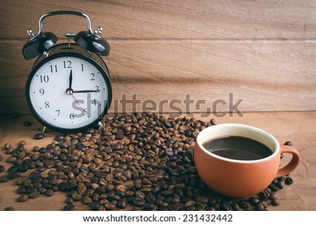Dark coffee and roasted coffee beans on wooden background.