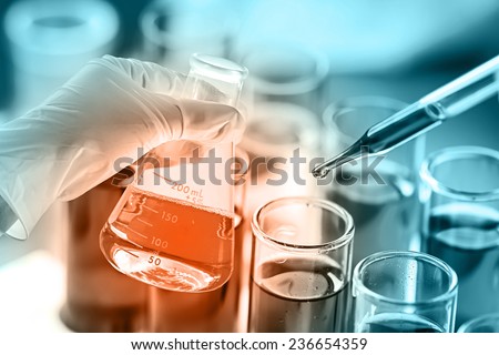 scientist dropping the reagent into test tube for reaction testing in chemical laboratory.