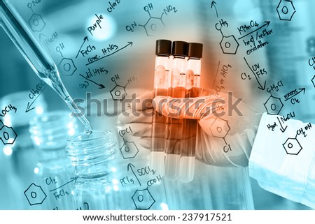 Researcher is holding the test tube, with chemical equations background, in laboratory