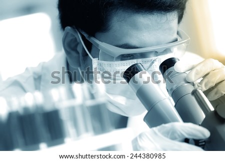 chemist using microscope to analyze the sample at laboratory