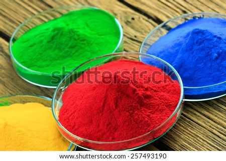 The pile of powder coating on glass plate, on wooden background.