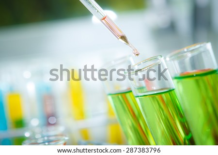 A researcher dropping the clear reagent into test tube for reaction testing in chemical laboratory.