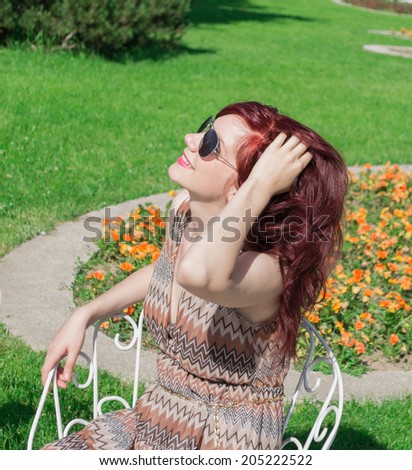 Beautiful young woman resting on a chair outdoors in a park