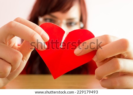Young woman in depression tearing heart