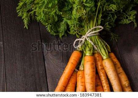 Bunch of ripe carrots on a black wooden background