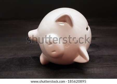 Piggy coin bank on black wooden background. Ceramic piggy coin bank for money savings, financial security or personal funds concept.