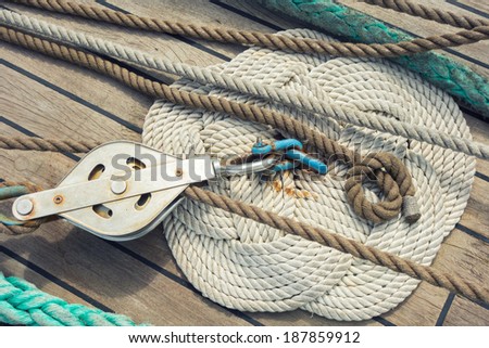Rope braided in celtic knot work shape on a wooden sailing ship floor with steel pulley