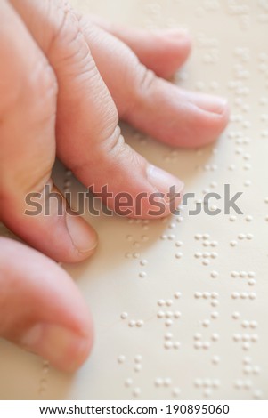 Close up of male hand reading braille text
