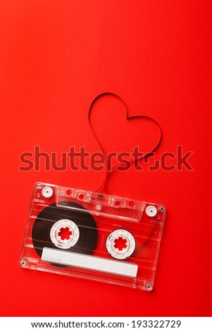 Vintage audio cassette with loose tape shaping a heart on red background
