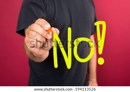 Young casual man writing the word NO on glass board with marker