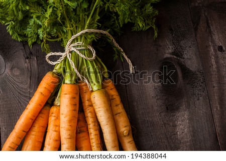 Bunch of ripe carrots on a black wooden background