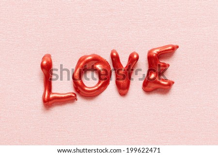 Word LOVE spelled in red glittering nail polish