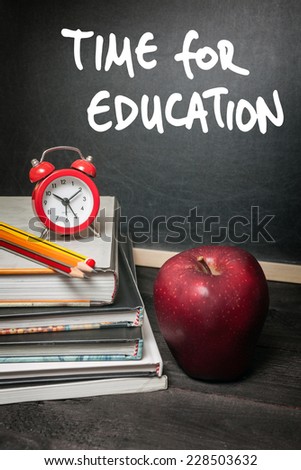 Apple on books and time for education handwritten on the chalkboard in the background