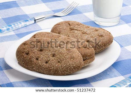 Dish of bread and glass of milk on a blue cloth. Close up shoot