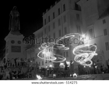 Jugglers with fire, in the square of flowers  in rome italy with the statue of Giordano Bruno (a philosopher who was set on fire in this square by the catholic church for his thoughts)