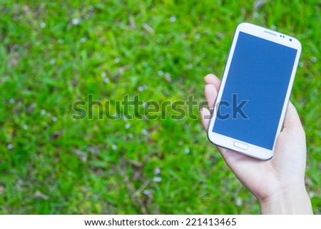 Closeup of female hands using a smart phone, green nature background