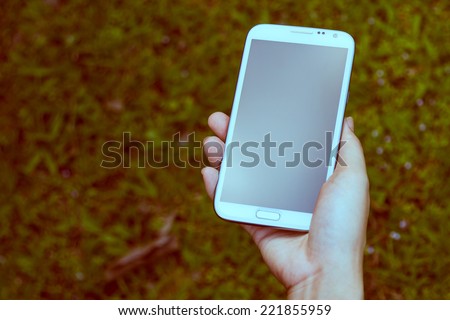 Closeup of female hands using a smart phone, green nature background