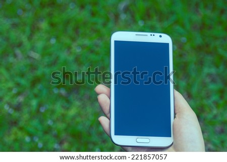 female hands using a smart phone, green nature background