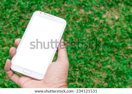 blank screen mobile phone in hand on green grass background
