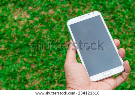 mobile phone in hand on green grass background