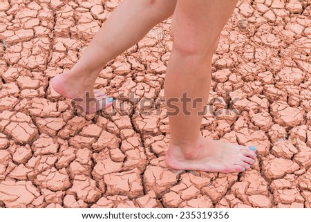 Nake woman foot walk on walk on cracked earth background